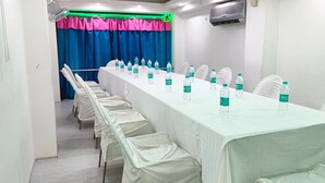 A conference room with a long table, white chairs, and water bottles.