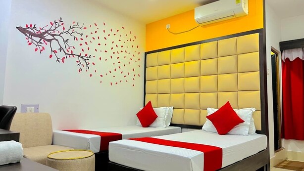 A hotel room with two beds, a sofa, a wall mural, and an air conditioning unit.