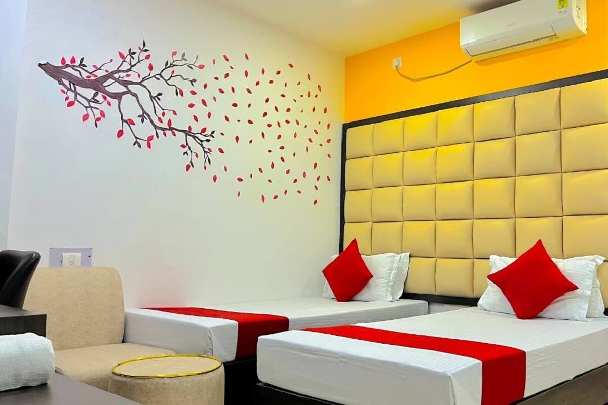 A hotel room with two beds, a sofa, a wall mural, and an air conditioning unit.