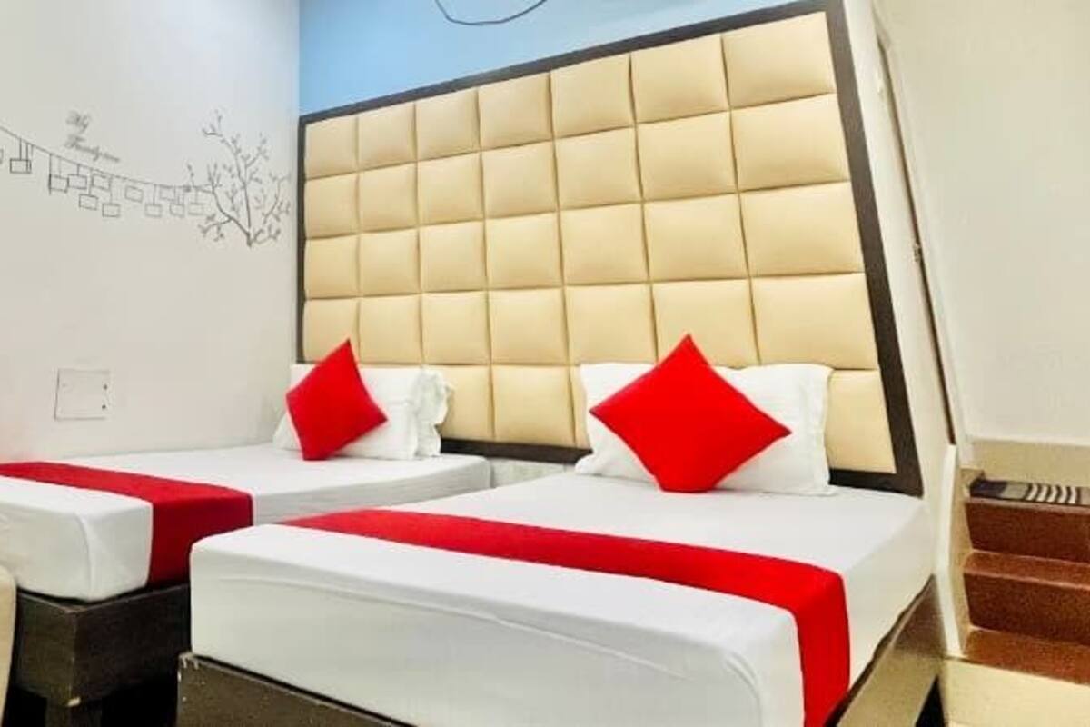 A hotel room with two beds, a headboard, a wall with a simple design, and a staircase.