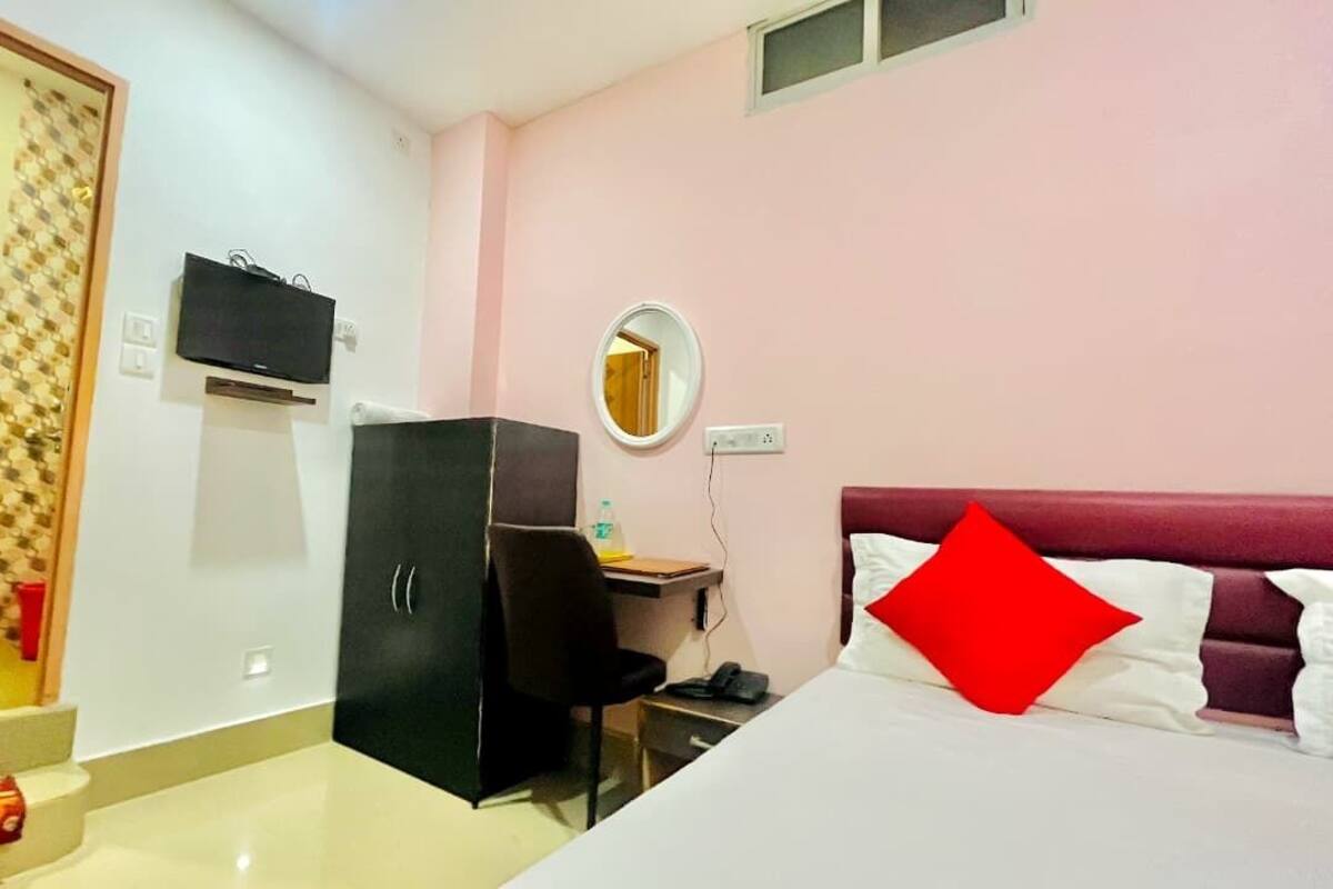 A bedroom with a bed, a desk, a wardrobe, and a bathroom.