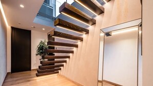 A modern staircase with wooden steps and integrated lighting, leading to a second floor.