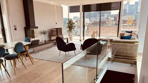 A modern living room with a glass railing, a dining area with chairs, and a sofa.