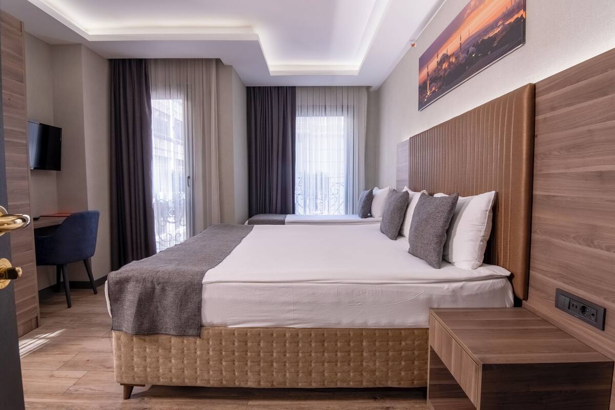 A hotel room with a large bed, a desk, and a TV.