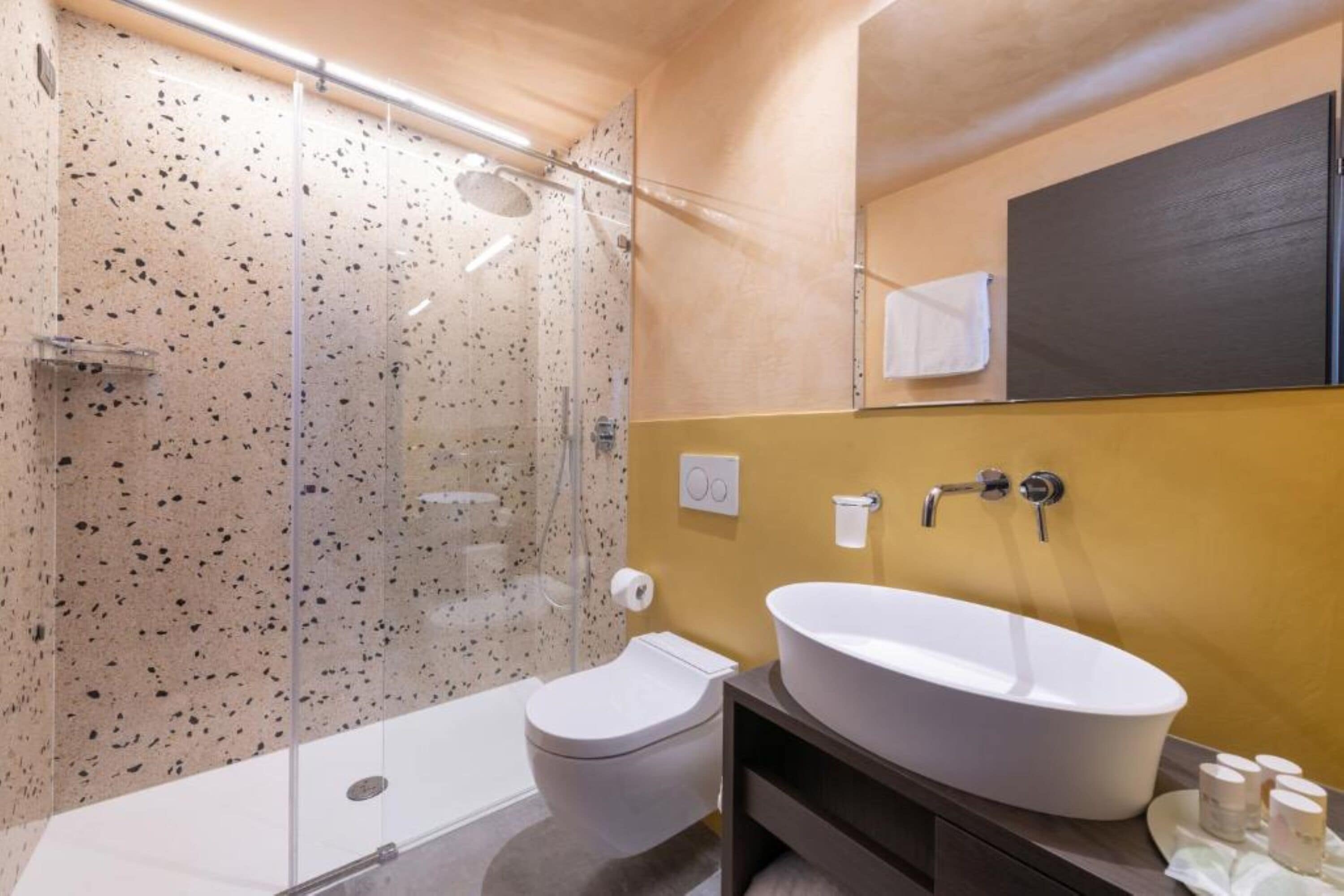 Un baño moderno con una bañera independiente, un inodoro y una ducha con mampara de cristal.