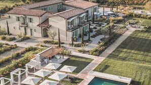 Una villa moderna con piscina, mobiliario de exterior y un jardín cuidado.