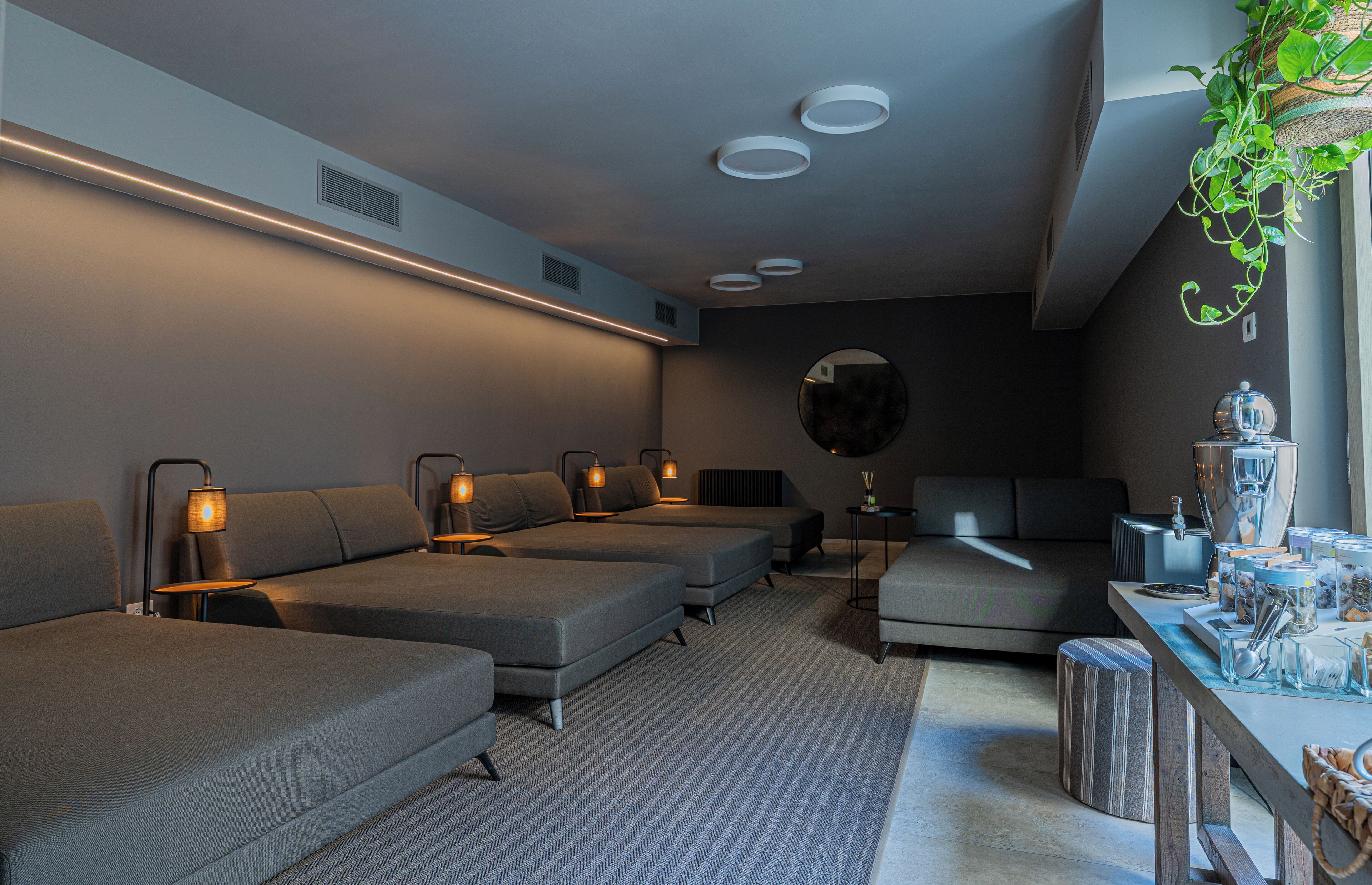 A modern, well-lit room with three sofas, a small table, and a hanging plant.