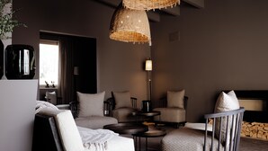 Una sala de estar moderna con un sofá, sillones, una mesa de centro, una lámpara de pie y una lámpara colgante.
