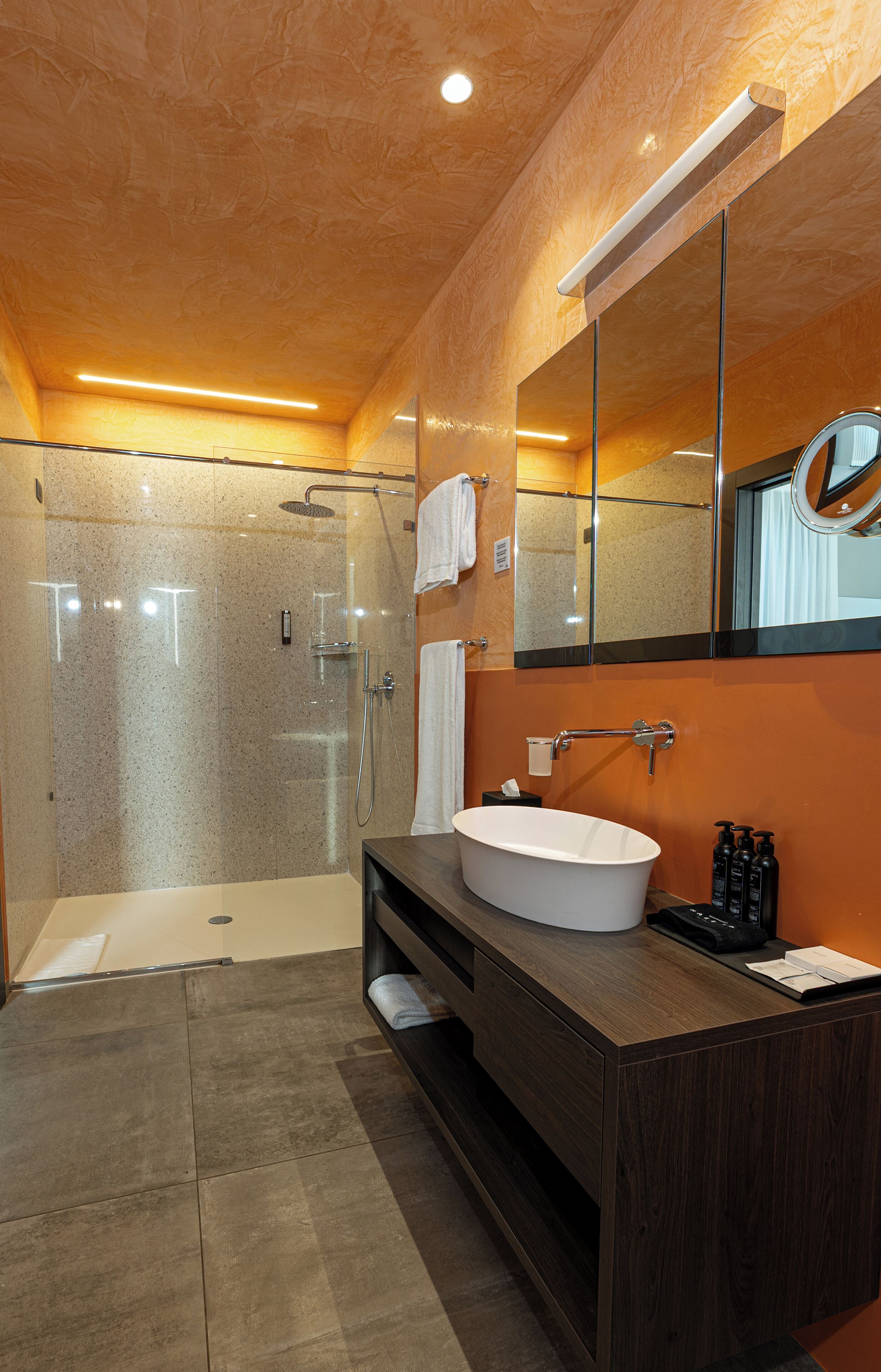 Un baño moderno con ducha de vidrio, una bañera independiente y un tocador con un espejo grande.