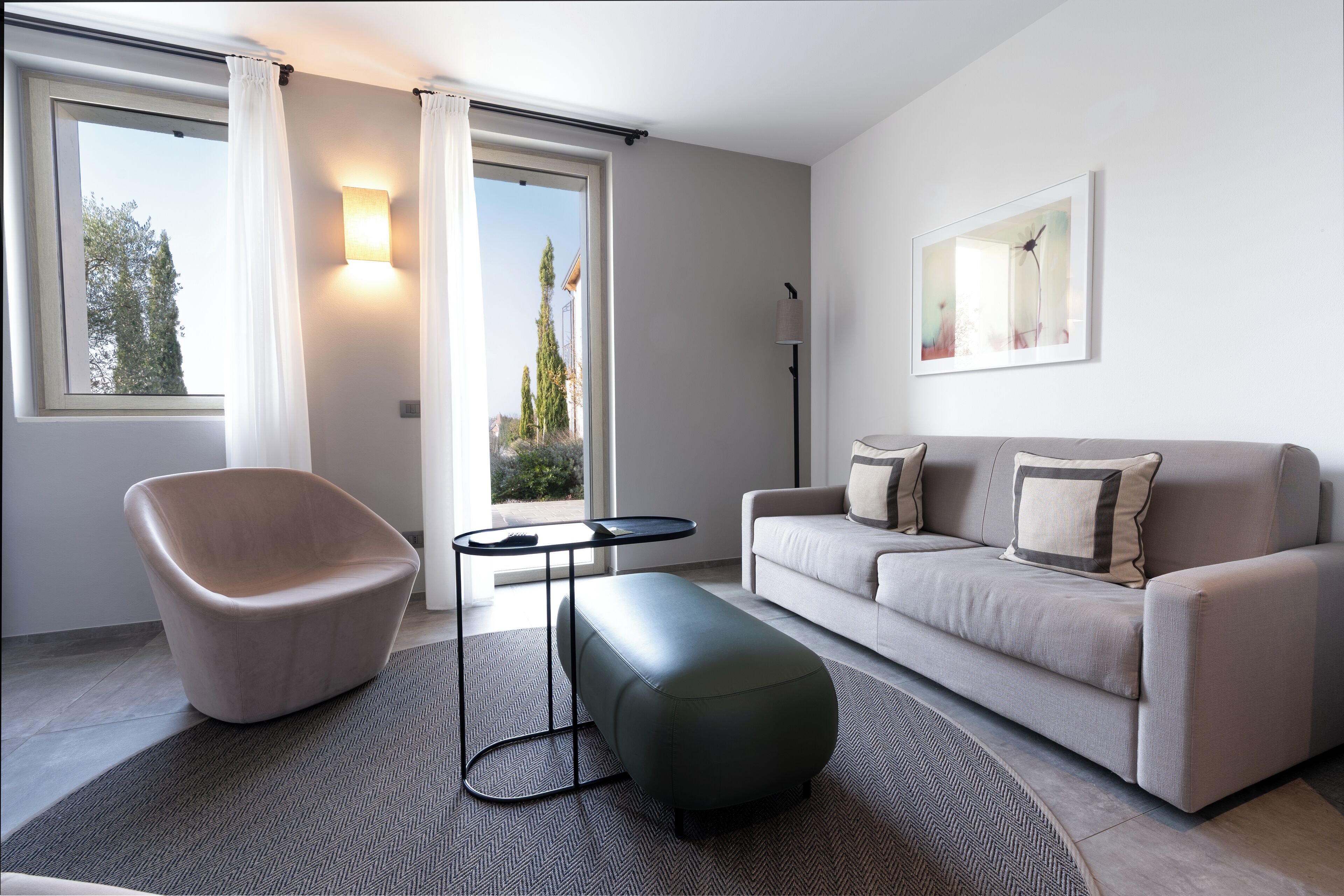 A modern living room with a sofa, a chair, a coffee table, and a large window with curtains.