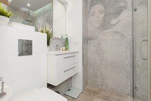 A modern bathroom with a shower, a sink, and a vanity. - Bright Apartment with Balcony | 15 min to Metro (Warszawa)