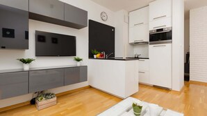 Una cocina moderna con gabinetes blancos, encimera negra y horno integrado.