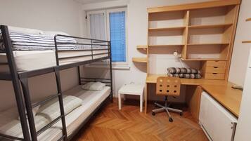 A bunk bed room with a desk, chair, and shelving unit.