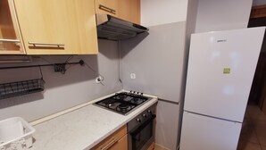 A compact kitchen with a gas stove, oven, and a white refrigerator.