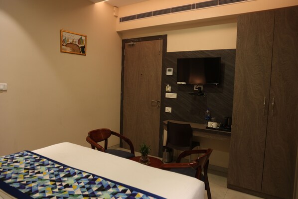 Une chambre d’hôtel équipée d’un lit, d’un bureau, d’une chaise, d’une télévision et d’une armoire.