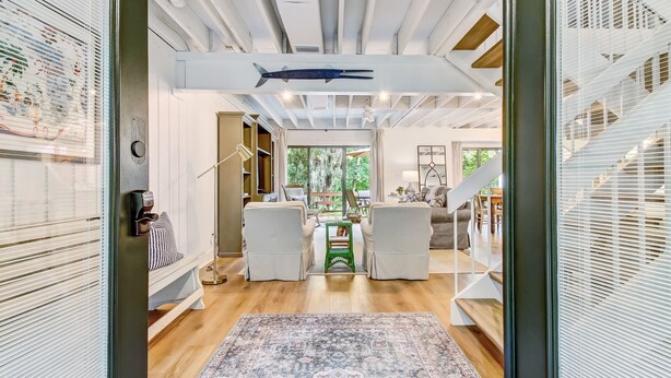 Un interior moderno con piso de madera, un tapete estampado y una escalera que conduce a otro nivel.
