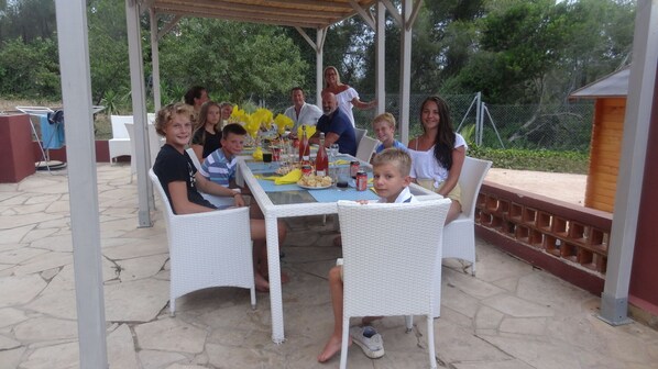 A group of people seated at a table with food and drinks, under a covered patio area. - Private Tennis-Voleyball-Basketball, Heated Pool, Sauna with Aromatherapy (El Corral d'en Tort)