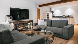 A modern living room with a grey sofa, a coffee table, and a TV. - Apartment with 180sqm - in a former quiet farmhouse (Weitnau)
