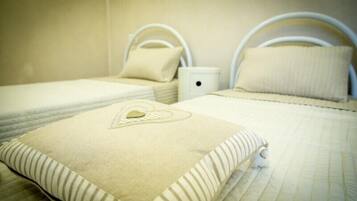 A hotel room with two beds, each with a white headboard and a pillow with a heart design.