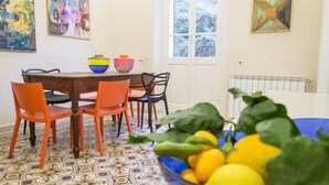 Ein Essbereich mit einem gemusterten Boden, einem Tisch mit Stühlen und einer Obstschale.