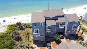 Un immeuble résidentiel à plusieurs étages avec vue sur la plage, doté de balcons et d’un espace de stationnement.