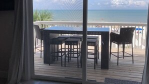 Un balcon avec vue sur l’océan, une table et des chaises.