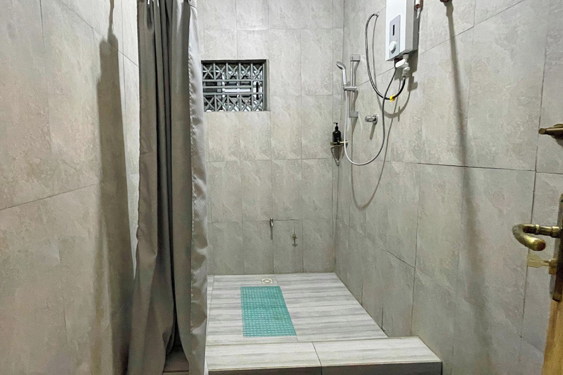 A shower stall with a tiled floor, a showerhead, and a control panel.