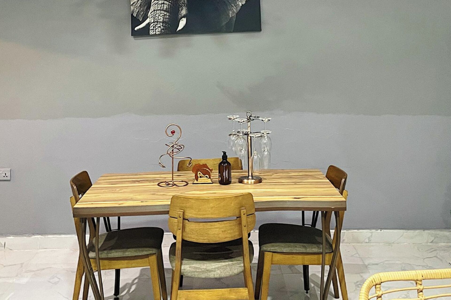 A dining table with four chairs, a wine rack, and a decorative metal sculpture.