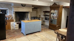 Une cuisine avec un mur en pierre, un îlot central en bois, une cuisinière et un four à micro-ondes.
