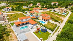 Un quartier résidentiel avec des maisons modernes, une piscine et un trampoline dans une cour clôturée.