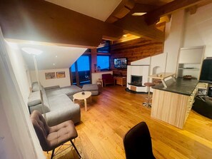 A modern living room with a sofa, chairs, a small round table, and a TV. - NaturSport Heutal (Unken)