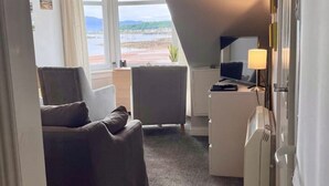 Una stanza con vista sulla spiaggia, una scrivania con una lampada, una sedia e un letto.