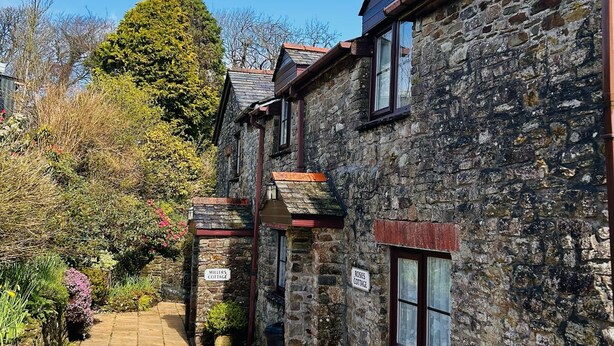 A stone cottage with a paved pathway leading to the entrance. - Millers cottage, a picturesque semi detached cottage with private garden (Woolfardisworthy)