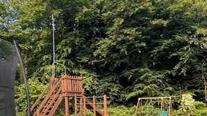 A playground with a slide, climbing structure, and a trampoline. - Millers cottage, a picturesque semi detached cottage with private garden (Woolfardisworthy)