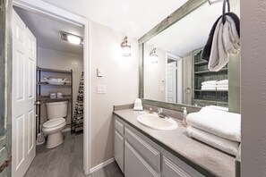 A bathroom with a toilet, sink, and mirror.