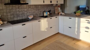 Eine moderne Küche mit weißen Schränken, einer schwarzen Dunstabzugshaube und einer gefliesten Spritzschutzwand.