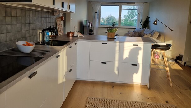 Eine moderne Küche mit weißen Schränken, einer Holz Arbeitsplatte und einem großen Fenster.