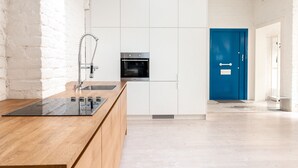 A modern kitchen with white cabinetry, a built-in oven, and a wooden countertop. - 2ndhomes Luminous 2BR Loft House w Sauna (Helsinki)