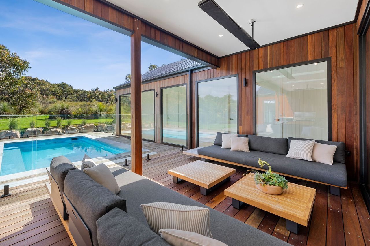 A modern outdoor living area with a pool, wooden deck, and seating.