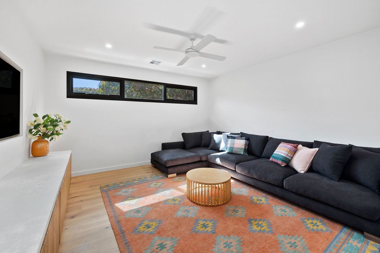 A modern living room with a sectional sofa, a round coffee table, and a ceiling fan.