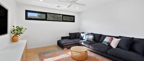 A modern living room with a sectional sofa, a round coffee table, and a ceiling fan.