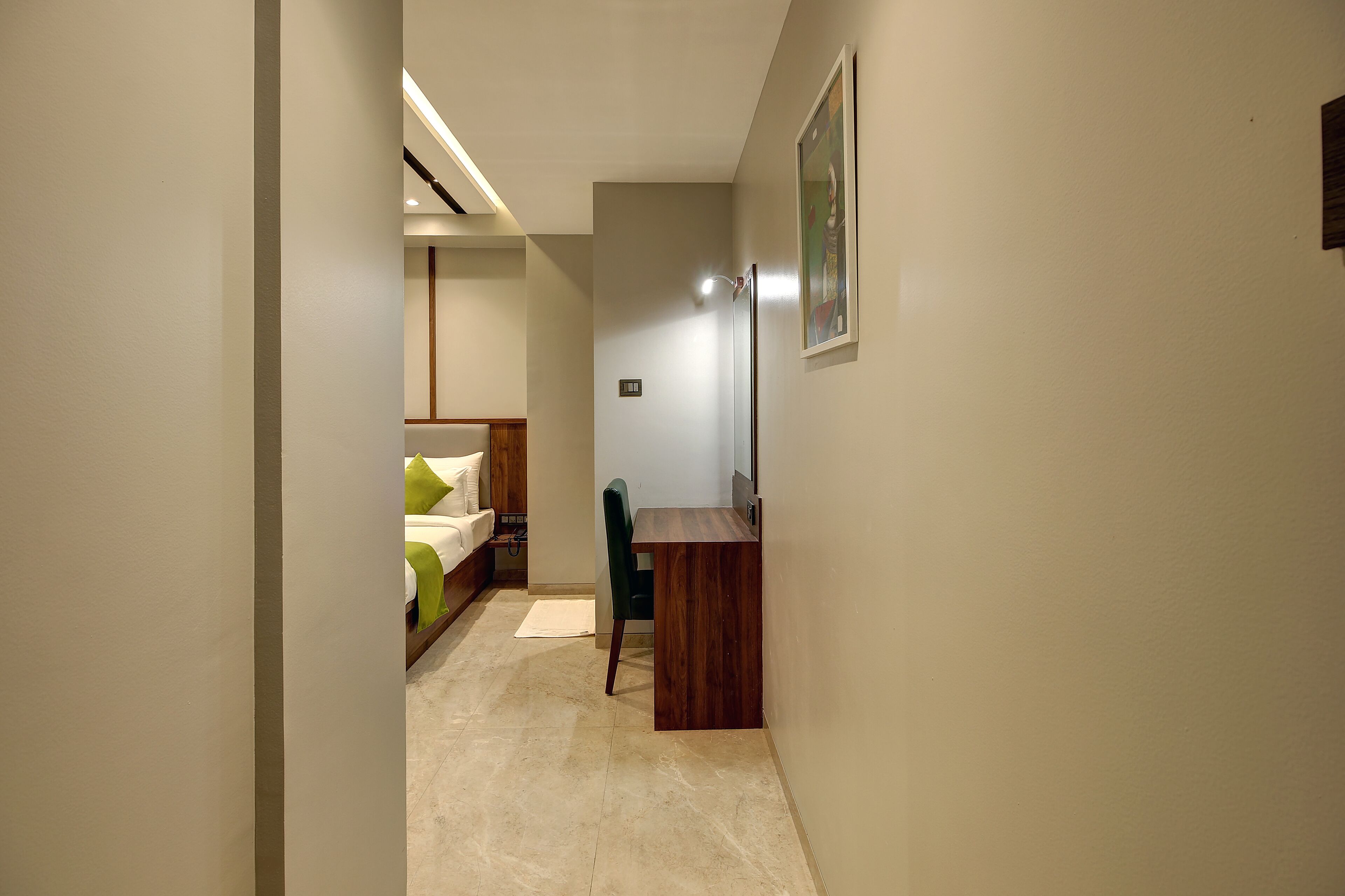 A narrow hallway with a bed on the left and a desk on the right.
