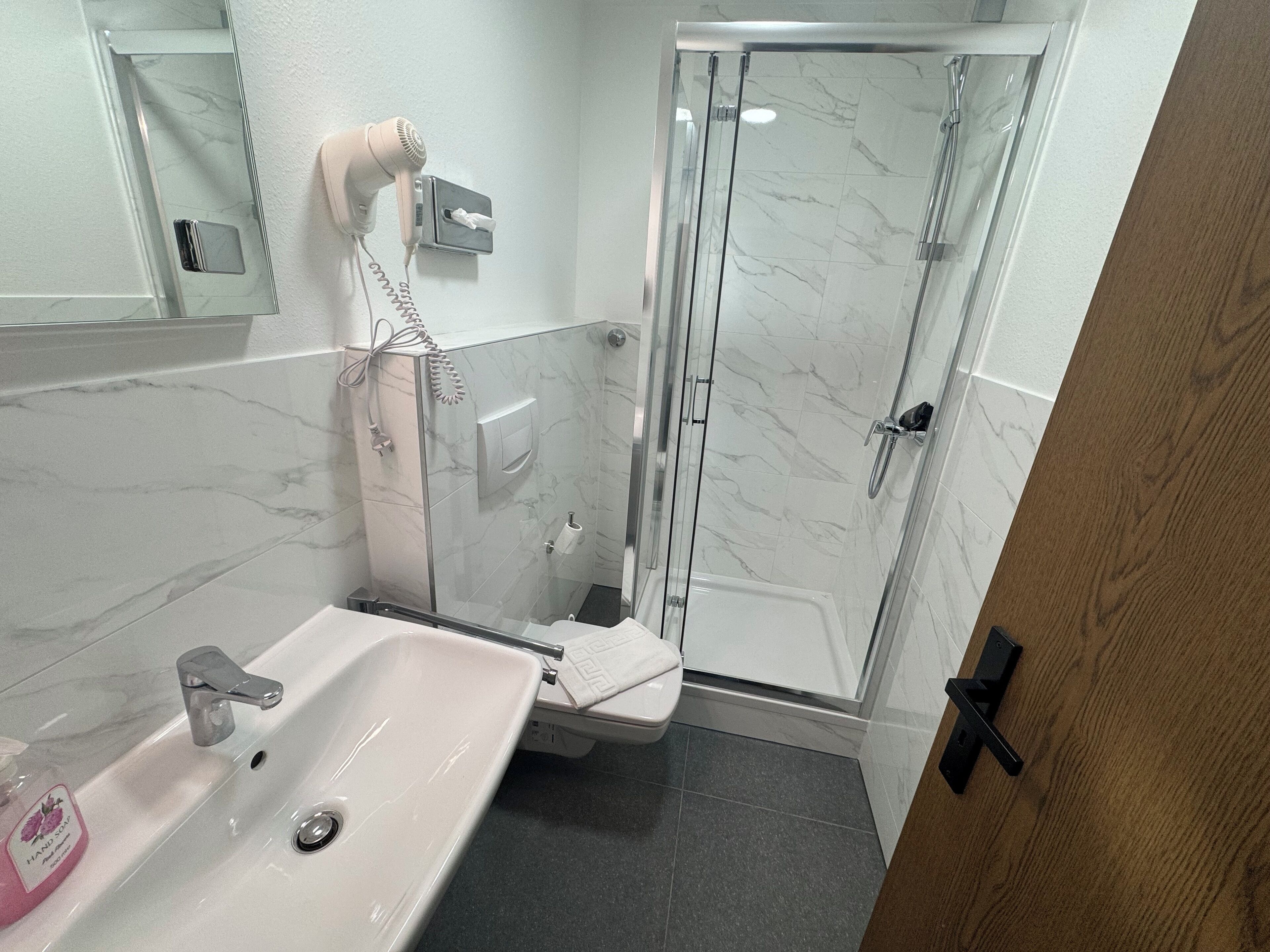 Un baño con lavabo, inodoro y cabina de ducha de vidrio.