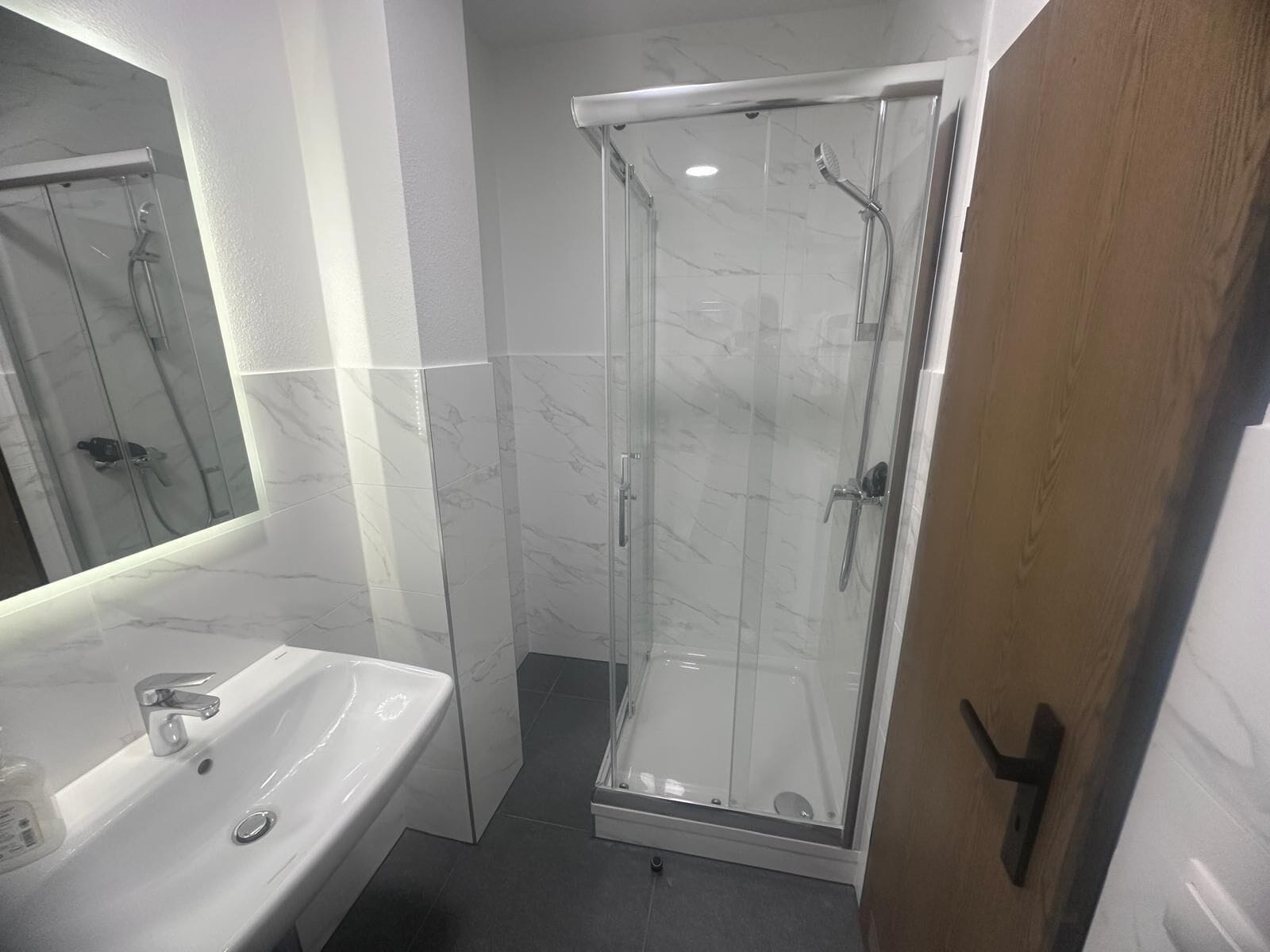 Un baño con ducha de vidrio, un lavamanos blanco y un espejo.
