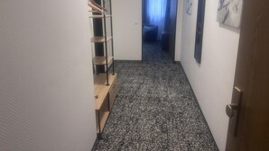 A narrow hallway with a black and white patterned carpet, a wooden desk with drawers, a metal shelf unit, and a door leading to another room. - Panorama Hotel Rheinkrone (Andernach)