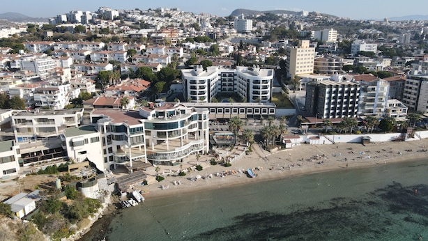 An aerial view of a coastal city with modern buildings, a beach, and clear waters.