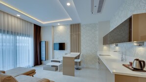 A modern hotel room with a living area, a dining area, and a kitchenette.