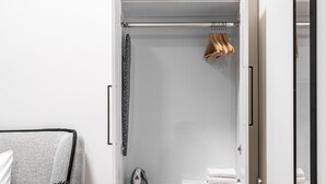 A modern room with a grey sofa, a small table with a plant, a wardrobe with a mirror, and a wooden floor. - JAFFA - Authentic Collection - By HOMY (Tel Aviv)