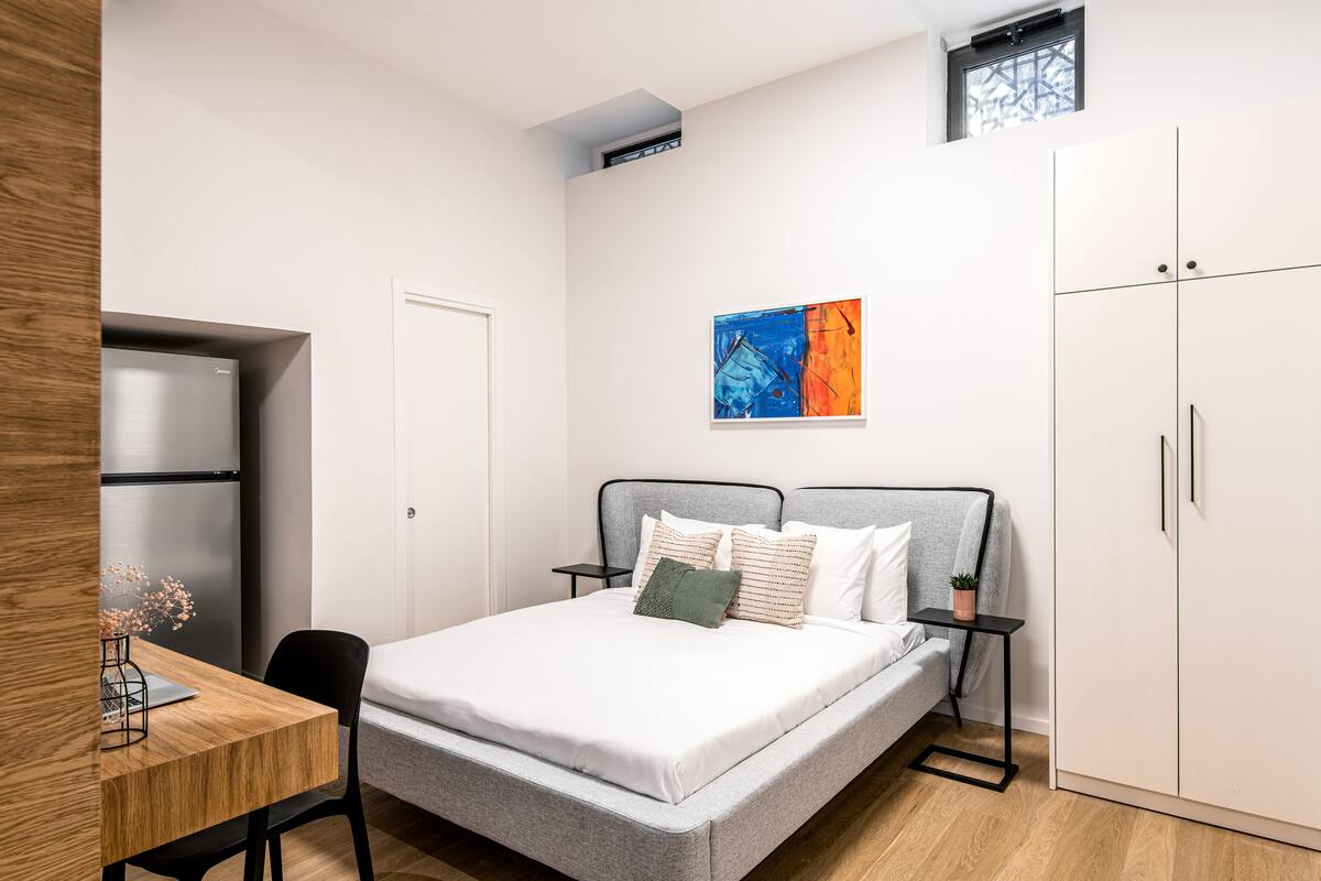 A modern bedroom with a bed, a desk, and a wardrobe.