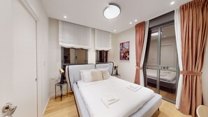 A modern bedroom with a large bed, a bedside table, a lamp, and a sliding glass door to a balcony. - JAFFA - Authentic Collection - By HOMY (Tel Aviv)
